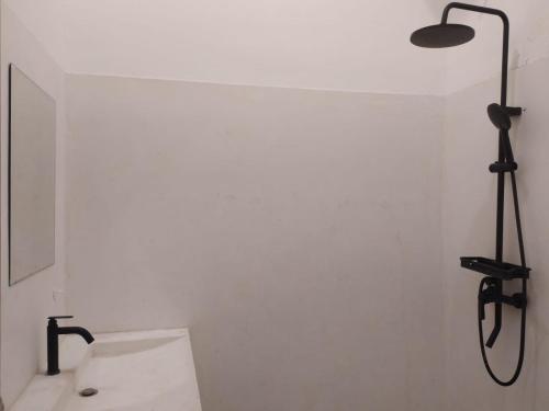 a bathroom with a shower and a sink and a light at Wanderlust Hostel Mandalika in Kuta Lombok
