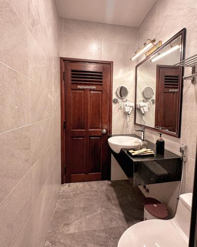 a bathroom with a toilet and a sink and a wooden door at L'amour Stay Dalat in Xuan An