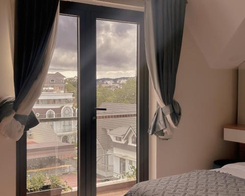a bedroom with a window with a view of a building at L'amour Stay Dalat in Xuan An
