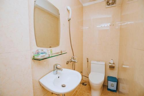 een badkamer met een wastafel, een toilet en een spiegel bij Thanh Loan Hotel DL - by BAY LUXURY in Da Lat