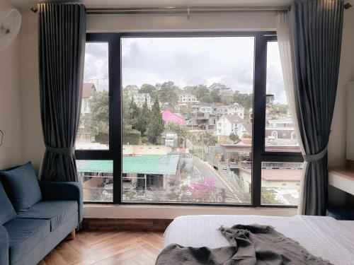 a room with a large window with a blue couch at L'amour Stay Dalat in Xuan An