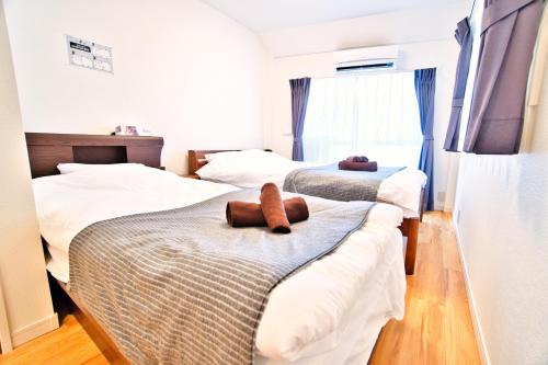 two beds in a bedroom with two brown teddy bears on them at Tokyo Oasis Heiwajima in Tokyo