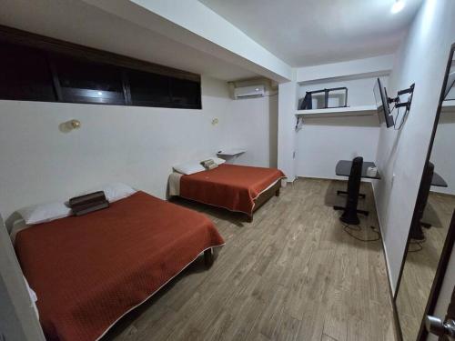 a hotel room with two beds and a desk at 2 Recamaras con clima y cocina centrico, wifi, tv smart in Ciudad Valles