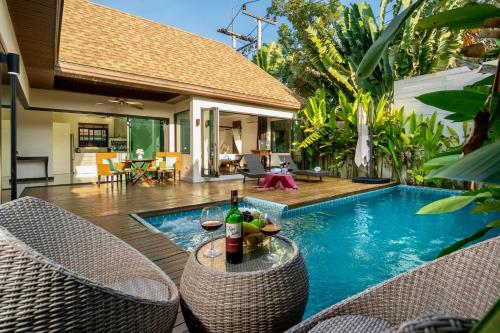 a pool with a table with a bottle of wine at Sanook dream villas Nai Harn Beach in Rawai Beach