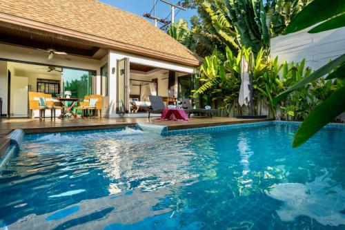 a swimming pool in front of a villa at Sanook dream villas Nai Harn Beach in Rawai Beach