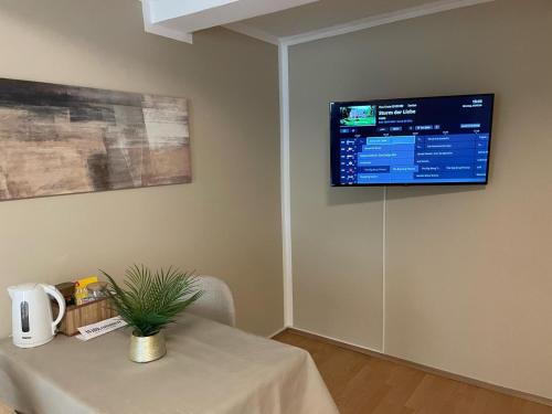 a room with a table and a television on the wall at Gemütliche Appartement 4 - mit Küche und Bad zur Eigennutzung -Schuster Homes- in Alvesse