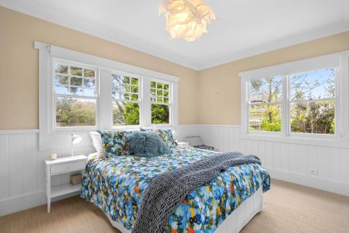 a bedroom with a bed and two windows at Munday Beach Retreat - Walk to Torquay Surf and Shops in Torquay