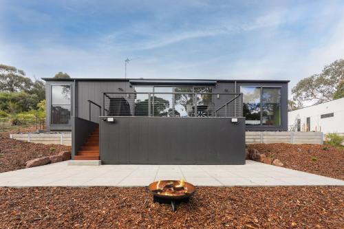 a small black house with a bowl in the yard at Banjo Treehouse in Hepburn Springs