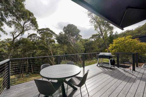 a deck with a table and chairs and a grill at Banjo Treehouse in Hepburn Springs