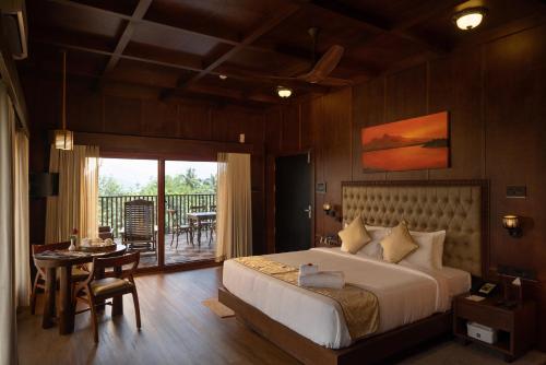a bedroom with a bed and a table and a balcony at Au Revoir Wellness Resort, Malampuzha in Palakkad