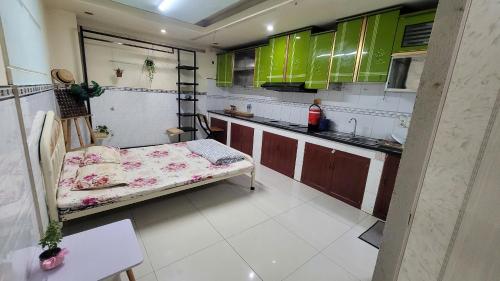 a small kitchen with green cabinets and a bed in it at Homestay Fairy's House in Ho Chi Minh City