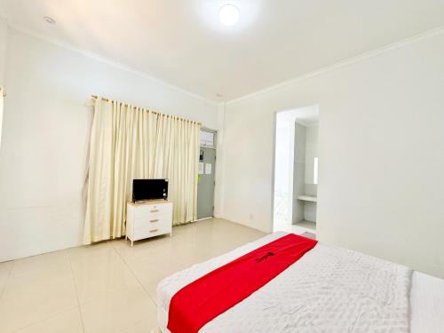 a white bedroom with a bed and a television at RedDoorz at Politeknik Pelayaran Surabaya in Surabaya