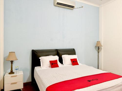 a bedroom with a bed with red pillows on it at RedDoorz at Politeknik Pelayaran Surabaya in Surabaya