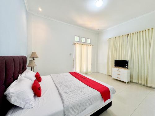 a bedroom with a bed with red pillows and a television at RedDoorz at Politeknik Pelayaran Surabaya in Surabaya