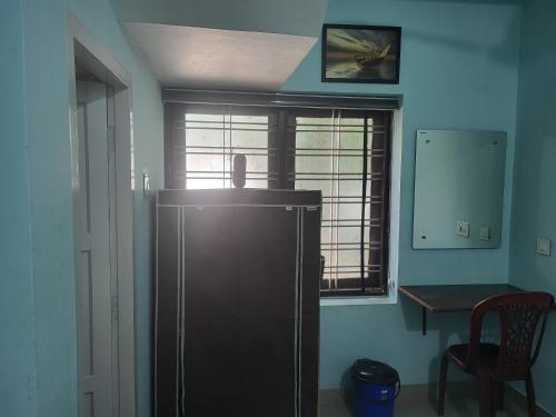 a refrigerator in a room with a table and a window at MIG Bliss in Fort Kochi