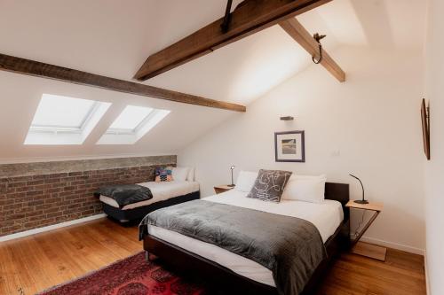 a bedroom with two beds and a brick wall at Boutique Warehouse living in West Hobart in Hobart