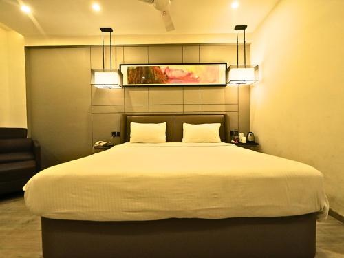 a bedroom with a large white bed with two pillows at D R Utthama Nellore - AM Hotel Kollection in Nellore