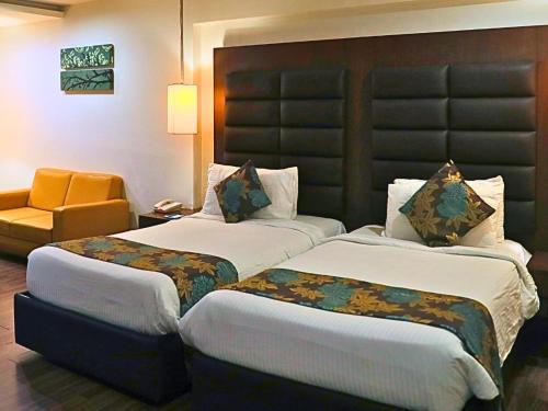 a hotel room with two beds and a chair at D R Utthama Nellore - AM Hotel Kollection in Nellore