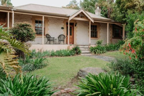 a house with a porch and chairs in the yard at Cole-Brook Cottage Historic House in McLaren Vale
