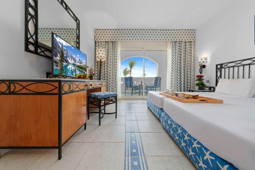 a bedroom with a bed and a tv and a desk at Domina Coral Bay Resort, Diving , Spa & Casino in Sharm El Sheikh