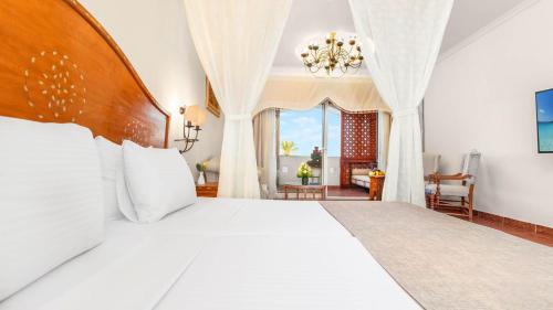 a bedroom with a large white bed with a chandelier at Domina Coral Bay Resort, Diving , Spa & Casino in Sharm El Sheikh