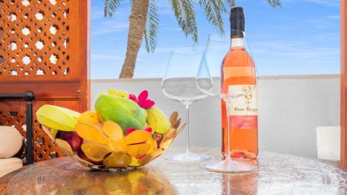 a bottle of wine and a bowl of fruit on a table at Domina Coral Bay Resort, Diving , Spa & Casino in Sharm El Sheikh