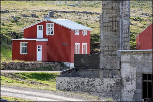 a red barn with a chimney on the side of a road at Hótel Djúpavík in Djupavik
