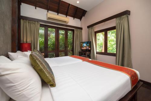 a bedroom with two white beds and a television at Legendha Sukhothai Hotel in Sukhothai