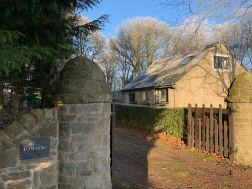 a house with a fence and a sign in front of it at Lowood Cottage in Edinburgh