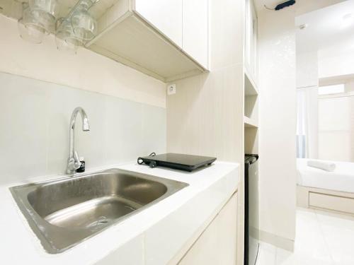a kitchen with a sink and a laptop on a counter at Minimalist and Homey Studio Room at Amartha View Apartment By Travelio in Semarang