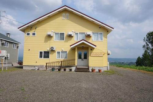a large yellow house with a front porch at The North Peak Nakafurano in Nakafurano
