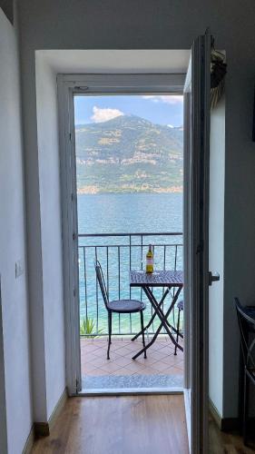 a door to a balcony with a table and a view of the ocean at Lake Mirror in Lezzeno