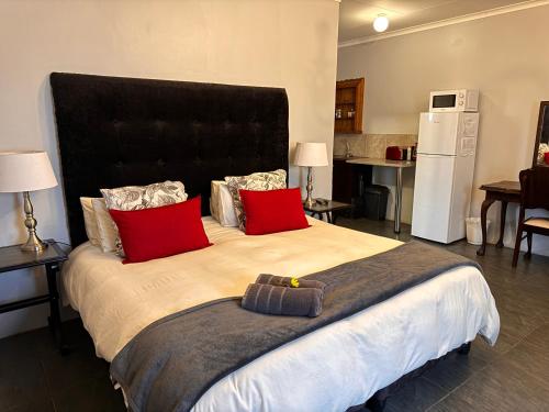 a bedroom with a large bed with red pillows at The Palms Venue & Accommodation in Cradock
