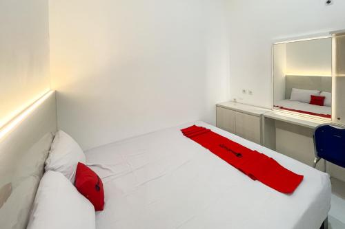 a white bed with red pillows in a room at RedDoorz at Pandu Raya Bogor by Madam M Place in Kalibata 1