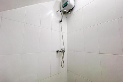 a shower in a white tiled wall with a shower head at RedDoorz at Pandu Raya Bogor by Madam M Place in Kalibata 1
