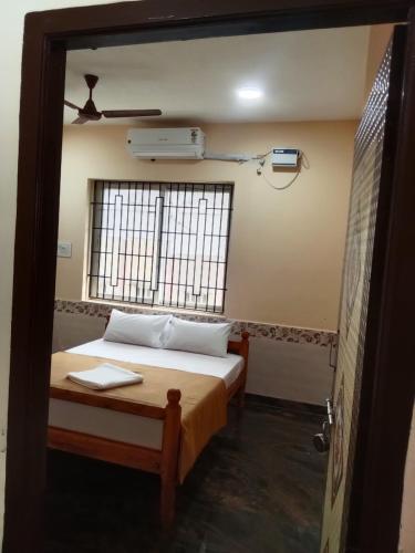 a bedroom with a bed and a window at LJ Rooms in Pākkam