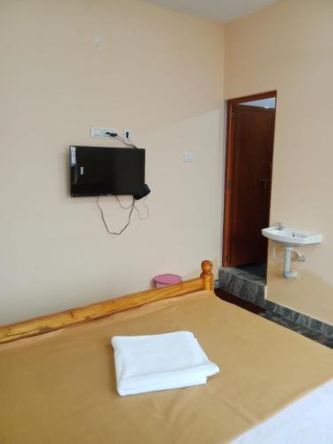 a room with a sink and a tv on the wall at LJ Rooms in Pākkam
