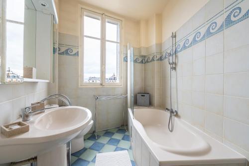 La salle de bains est pourvue d'un lavabo, d'une baignoire, d'un lavabo et d'un miroir. dans l'établissement Champs Elysées I Vue sur Tour Eiffel & Spacieux, à Paris