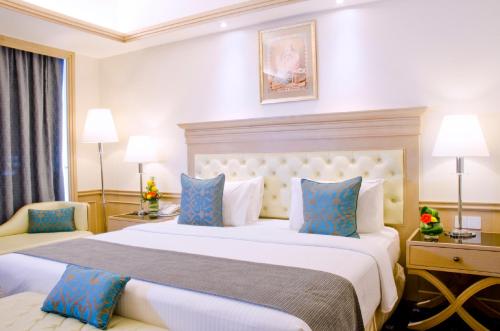 a hotel room with a large bed with blue pillows at Royale Chulan Penang in George Town