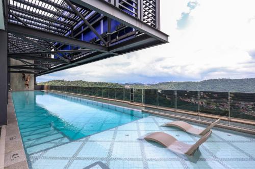 a swimming pool with two lounge chairs on top of a building at Mossaz Suites by MyKey in Petaling Jaya