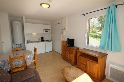a living room with a table and a kitchen at Gîte du bosquet in Égletons