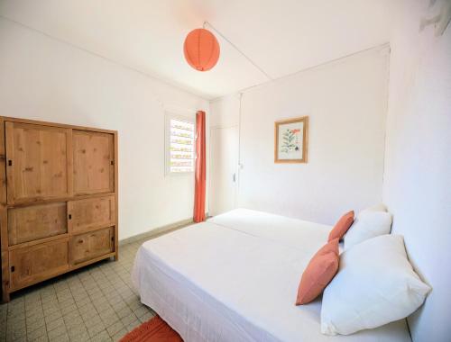 a bedroom with a bed and a wooden cabinet at Case Ti Piment - Accès privé à la plage in Saint-Gilles les Bains