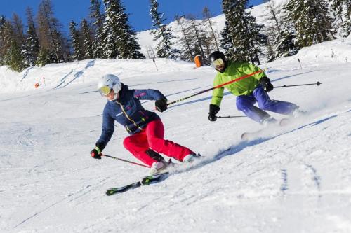 two people are skiing down a snow covered slope at Apartment in Achenkirch near Lake Achensee in Achensee