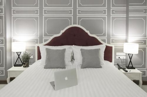 a bedroom with a bed with a laptop on it at Art Mai Gallery Nimman Hotel Chiang Mai in Chiang Mai