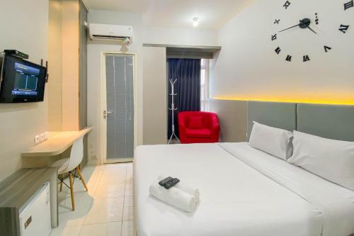 Habitación de hotel con cama y reloj en la pared en Comfortable 1BR without Living Room at Amartha View Apartment By Travelio, en Semarang