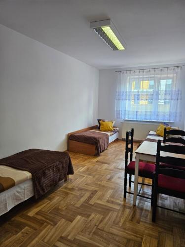 Un dormitorio con dos camas y una mesa y un sofá. en Hostel kamelarny dla seniorow z celodobowa opieka Wera, en Ząbki