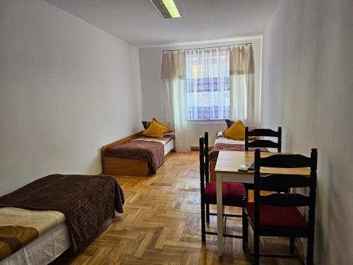 una habitación con dos camas y una mesa y sillas en Hostel kamelarny dla seniorow z celodobowa opieka Wera, en Ząbki