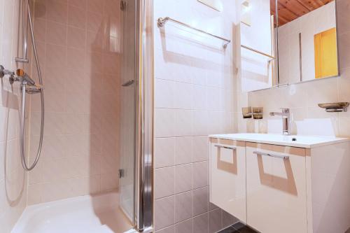 een witte badkamer met douche en wastafel bij Meinaz W 030 - QUIET apartment 7 pers in Veysonnaz