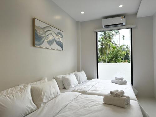 a white bedroom with two towels on a bed at Pisingha Pool Villa Khanom in Khanom