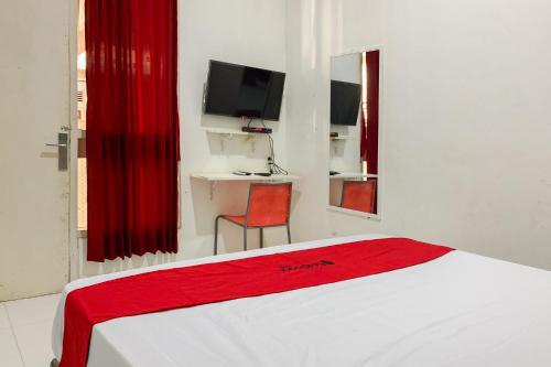 a bedroom with a bed with a red blanket on it at Reddoorz at Hotel Bahagia Pangandaran in Pangandaran